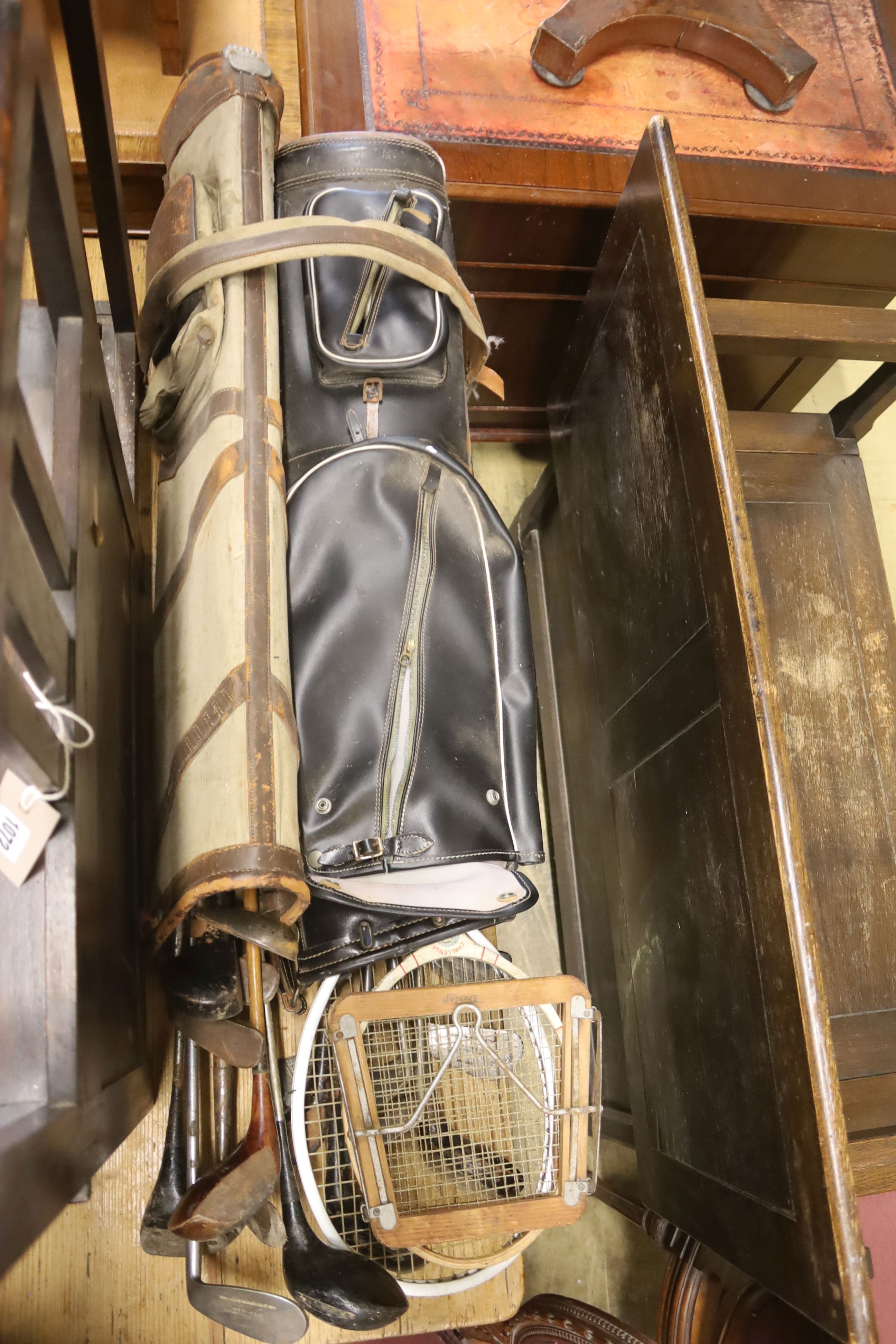 A 1920's oak hall seat together with a collection of vintage lacrosse sticks, golf clubs, etc.